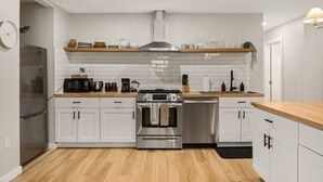 A modern kitchen with white cabinetry, stainless steel appliances, and a wooden countertop. - Pickleball, Pool, Games, Mins to Zilker, SoCo/DT (Austin)