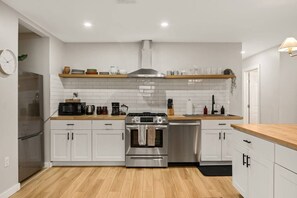 Eine moderne Küche mit weißen Schränken, Edelstahlgeräten und einer Holz Arbeitsplatte.