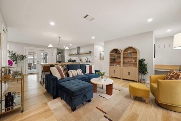A modern living room with a sectional sofa, a coffee table, and a yellow armchair. - Pickleball, Pool, Games, Mins to Zilker, SoCo/DT (Austin)