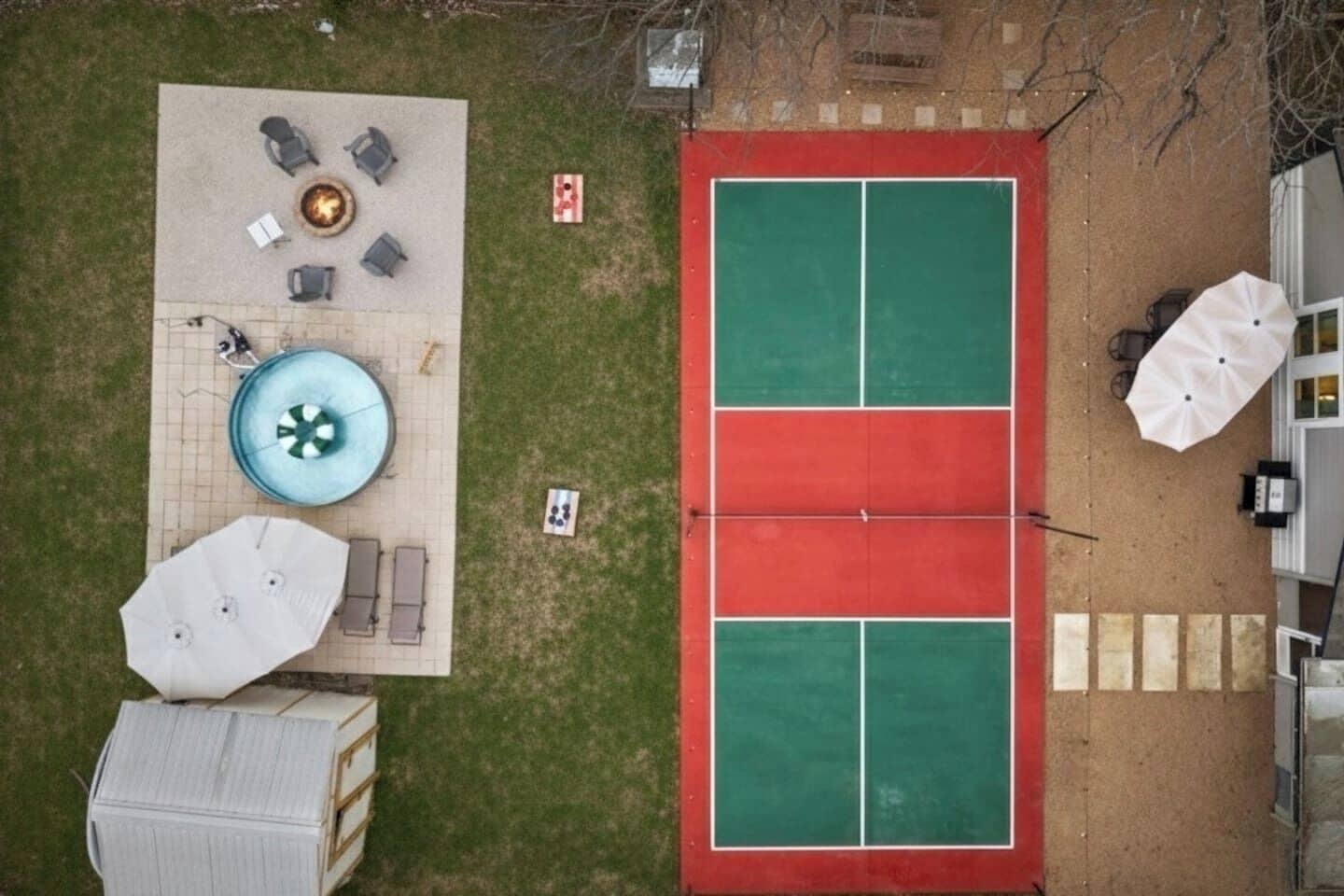 A rooftop with a swimming pool, outdoor seating, and a tennis court.