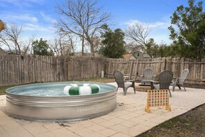 Ein Garten mit Whirlpool, Gartenmöbeln und Holzzaun.