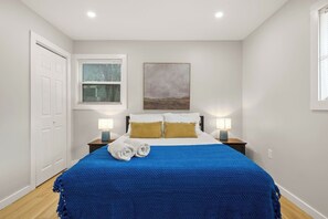 A bedroom with a bed, two bedside tables with lamps, a window with blinds, a door, and a painting on the wall. - Pickleball, Pool, Games, Mins to Zilker, SoCo/DT (Austin)