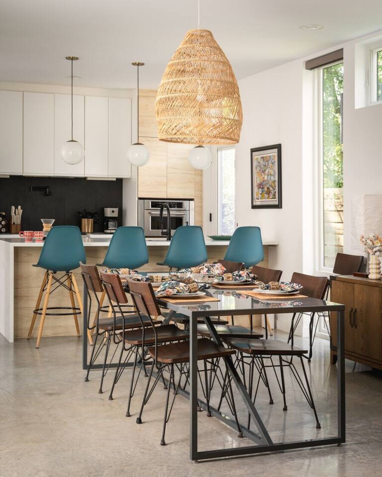 Une cuisine moderne avec des meubles blancs, un grand îlot central et un coin repas comprenant une table et des chaises en verre.