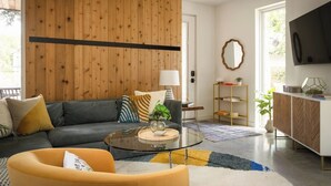 Una sala de estar moderna con un sofá, un sillón, una mesa de centro y un televisor montado en la pared.