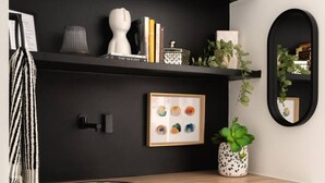 Una cocina moderna con armarios negros, un lavamanos de acero inoxidable y objetos decorativos en estantes.