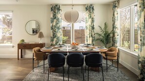 A dining area with a round table, four chairs, a bowl of fruit, and a hanging light fixture. - Pool, Mini-golf, Sauna, Movie, Gym | Sleep 18 (Austin)