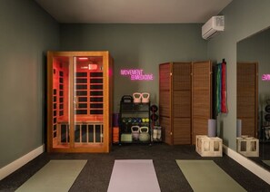 A room with a wooden cabinet, a shelf with kettlebells, and a neon sign. - Pool, Mini-golf, Sauna, Movie, Gym | Sleep 18 (Austin)