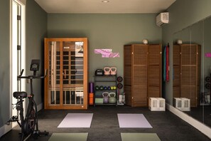 Ein Fitnessraum mit Trainingsgeräten, Matten und Stauraumschränken.