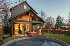 Ein modernes Haus mit überdachter Terrasse, Schwimmbad und gepflegtem Rasen.