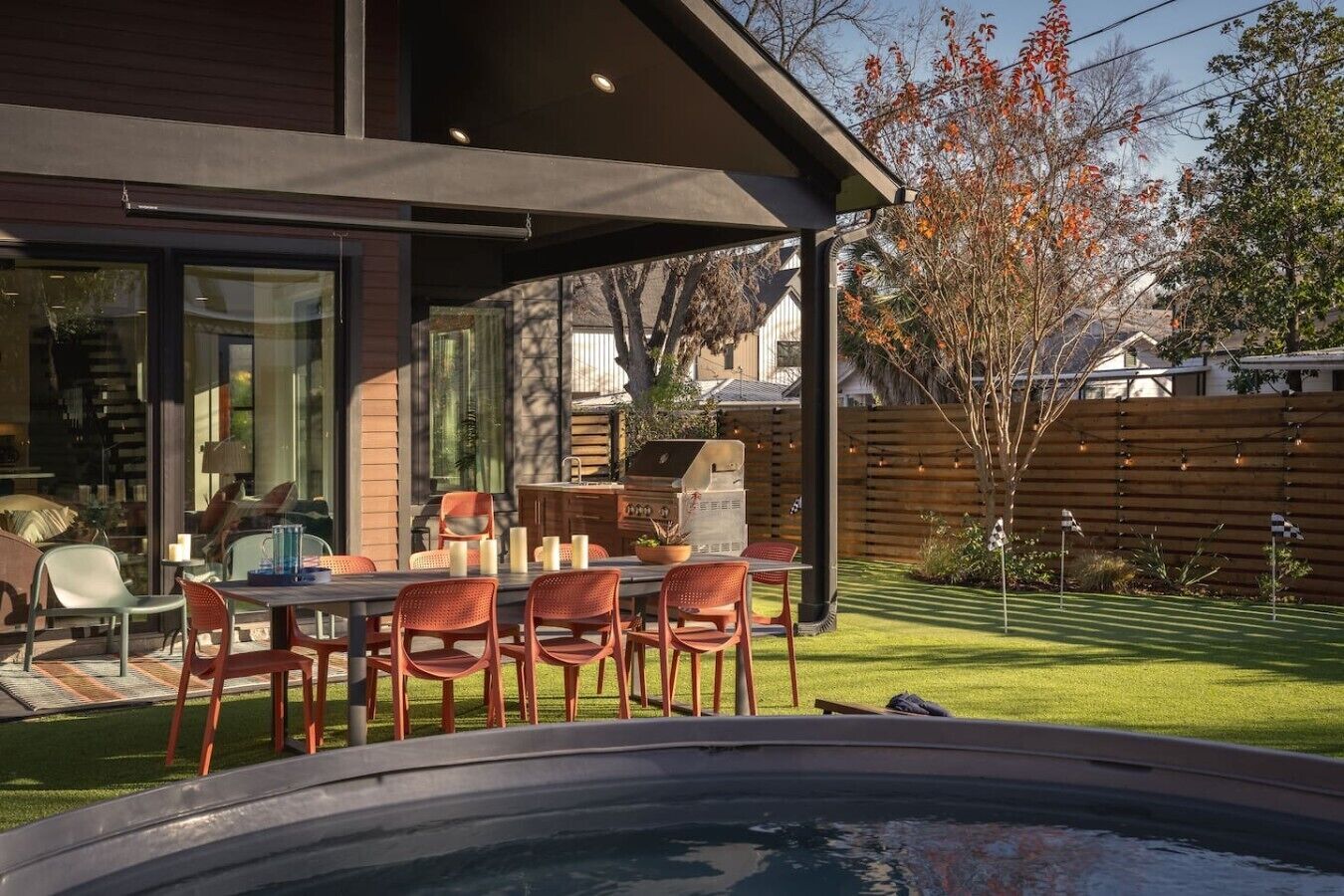 Een terras buiten met een eettafel en stoelen, een barbecue en een zwembad.