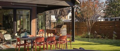 An outdoor patio with a dining table and chairs, a barbecue grill, and a swimming pool.