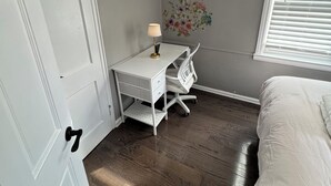 Quarto com cama, escrivaninha e janela.