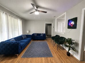 Ein Wohnzimmer mit Ecksofa, Deckenventilator, gemustertem Teppich und einer Topfpflanze.