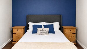 A bedroom with a bed, two nightstands, and a wall painted blue. - Family-Friendly 3BR – 1 Mi to Six Flags, AT&T Stadium & Globe Life Field (Arlington)