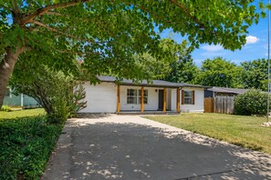 Eingeschossiges Haus mit Veranda, Garage und gepflegtem Rasen.