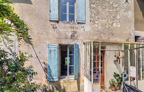 Edifici amb balcó, tancament de vidre i finestra amb persianes blaves.