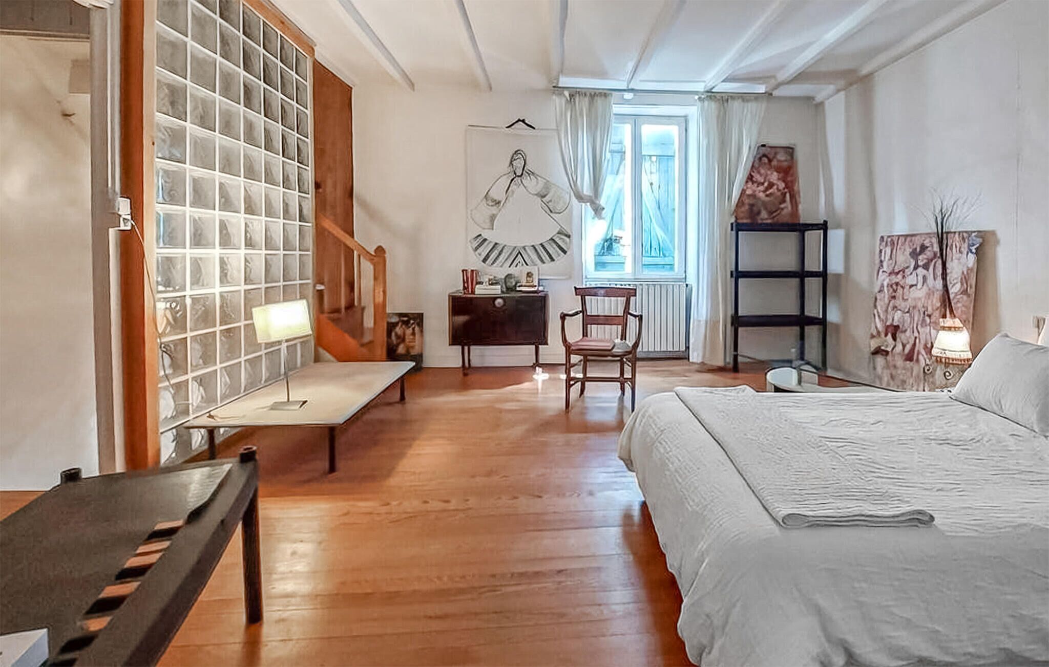 A room with a bed, a desk, a chair, a lamp, a window, and a wall with a poster.