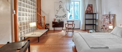 A room with a bed, a desk, a chair, a lamp, a window, and a wall with a poster.