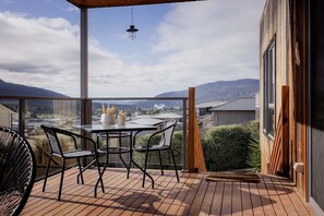 Un balcón con una mesa y sillas, con vistas a un paisaje montañoso.