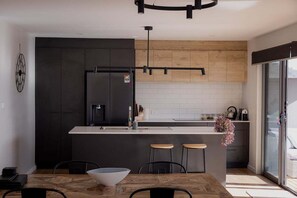 A modern kitchen with a central island, dark cabinetry, and a wooden accent wall.