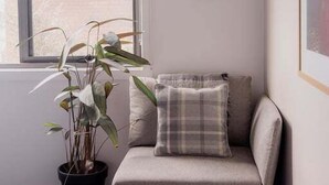 A corner room with a sofa, a potted plant, and a framed picture on the wall.