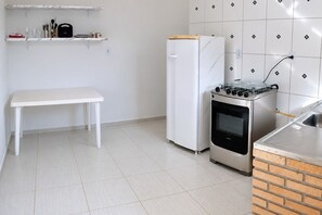 Cuina compacta amb una barra blanca, un frigorífic blanc, una cuina a gas i un forn de rajola.