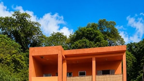Een gebouw met twee verdiepingen, een betonnen begane grond en een balkon op de bovenverdieping.