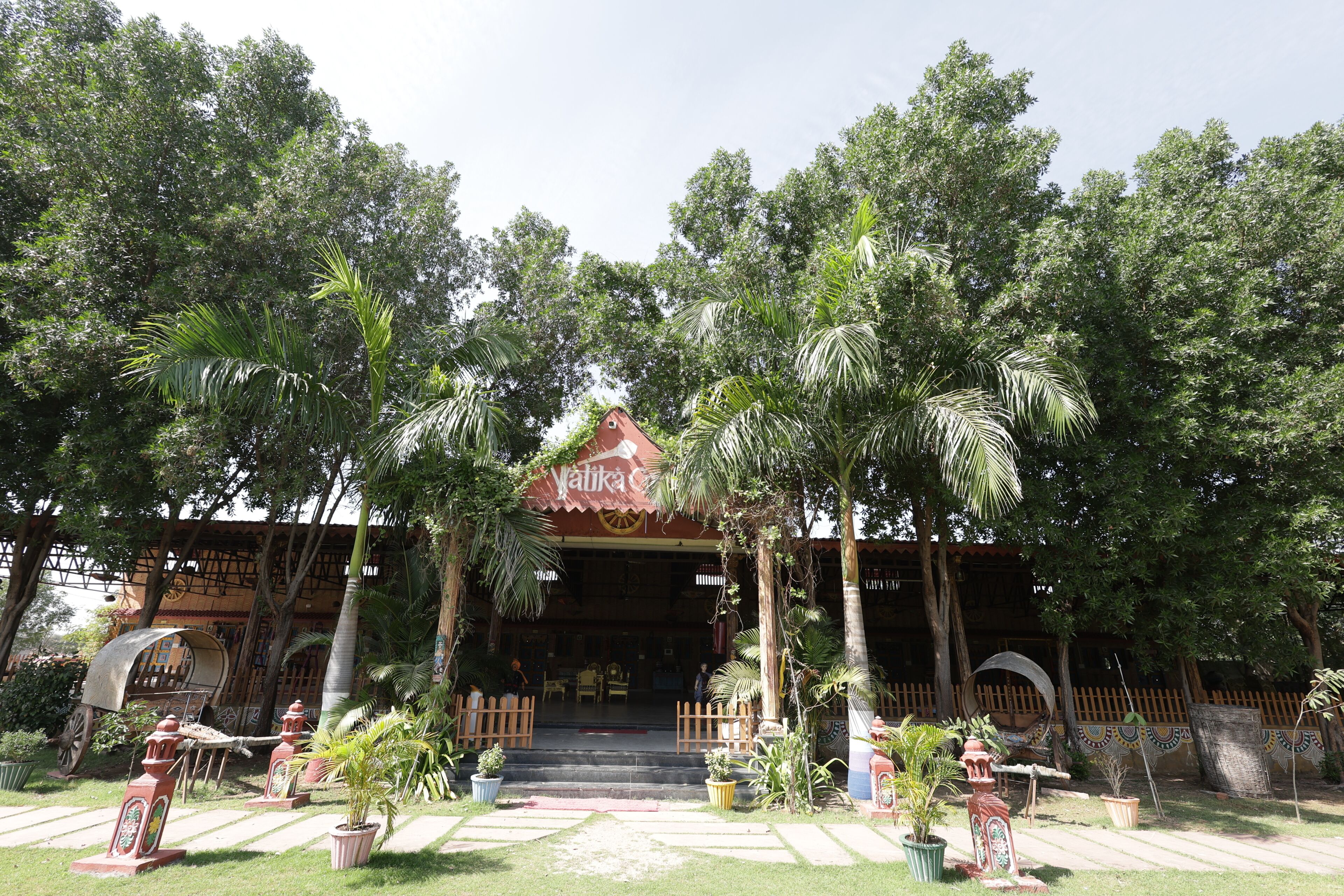 A building with a traditional design, surrounded by lush greenery and palm trees.