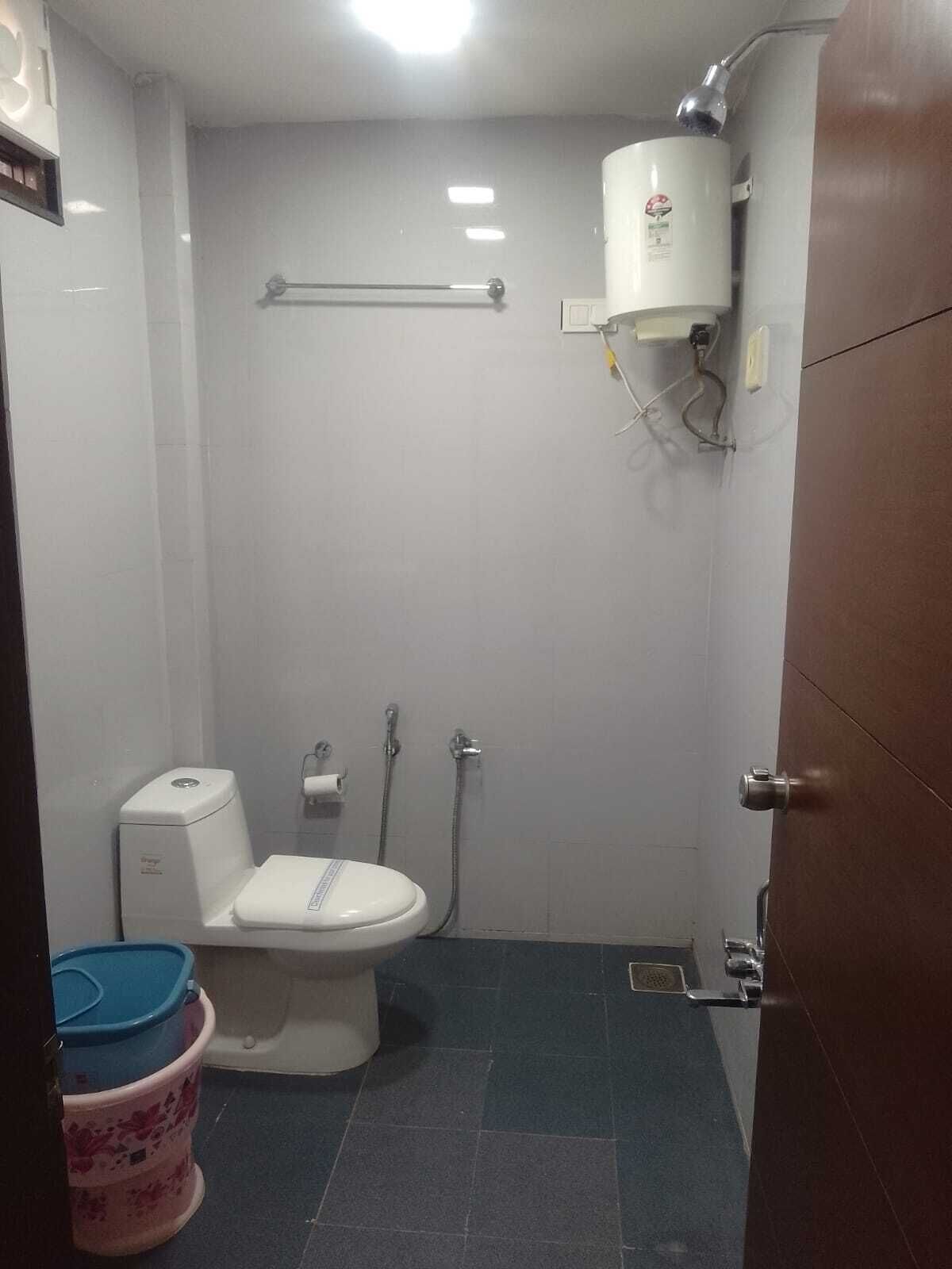 A small, enclosed bathroom with a toilet, bidet, and a water heater.