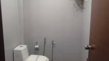 Un baño pequeño y cerrado con inodoro, bidé y calentador de agua.