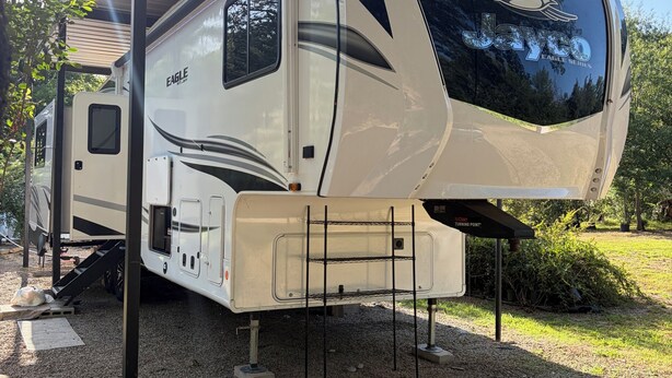 Ein Wohnmobil der Jayco Eagle Serie mit überdachtem Wohnbereich, einer Küche und einem Schlafbereich.