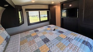 Ein Schlafzimmer mit einem großen Bett, einem Fenster, einem Fernseher und einer Tür.