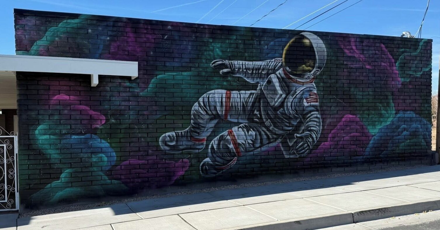 Une fresque représentant un astronaute sur un mur de briques.