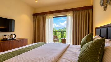 A hotel room with a bed, a television, a coffee maker, and a view of the outdoors.