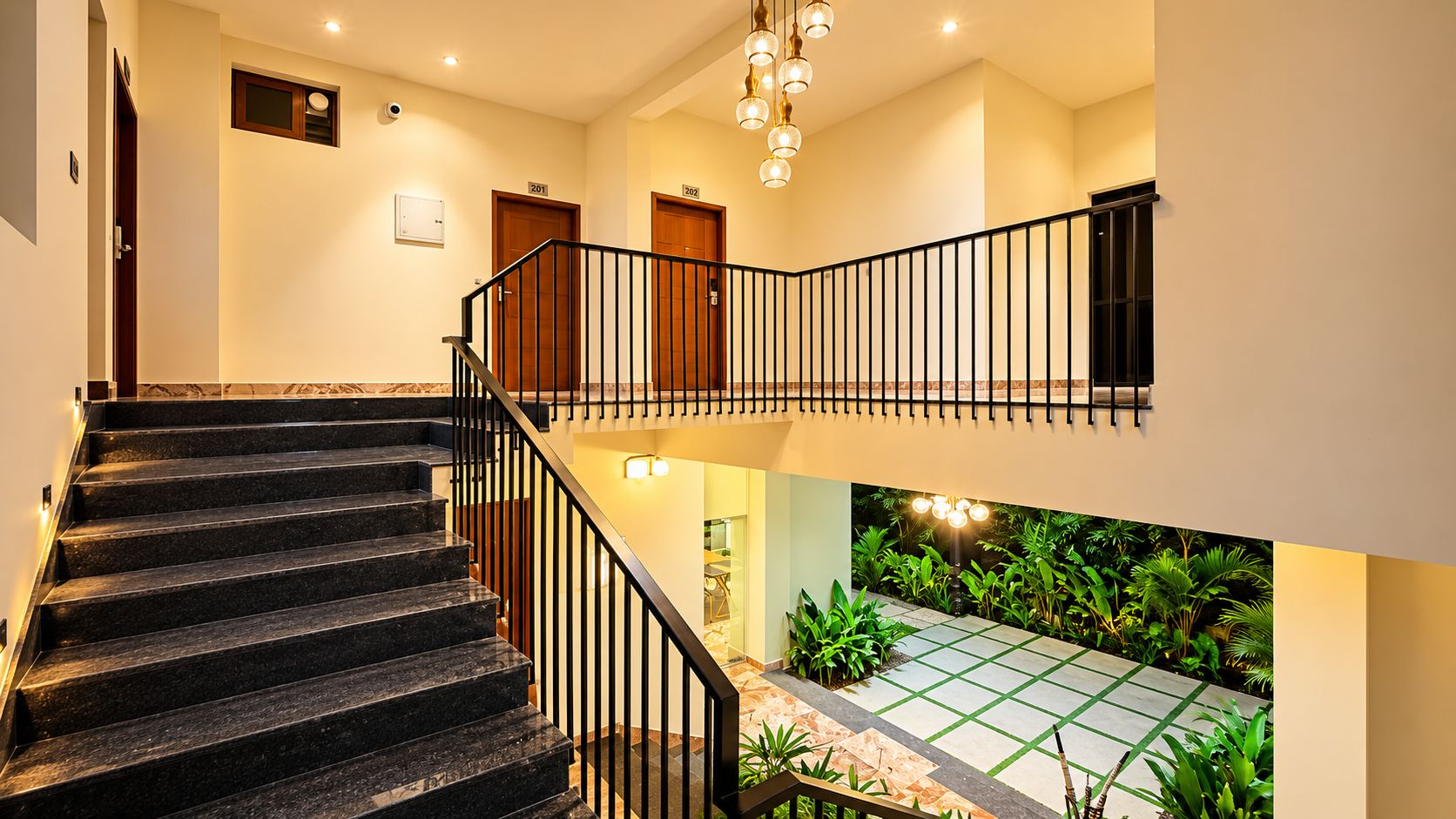 A multi-level interior with a staircase, doors, and a small outdoor garden area.