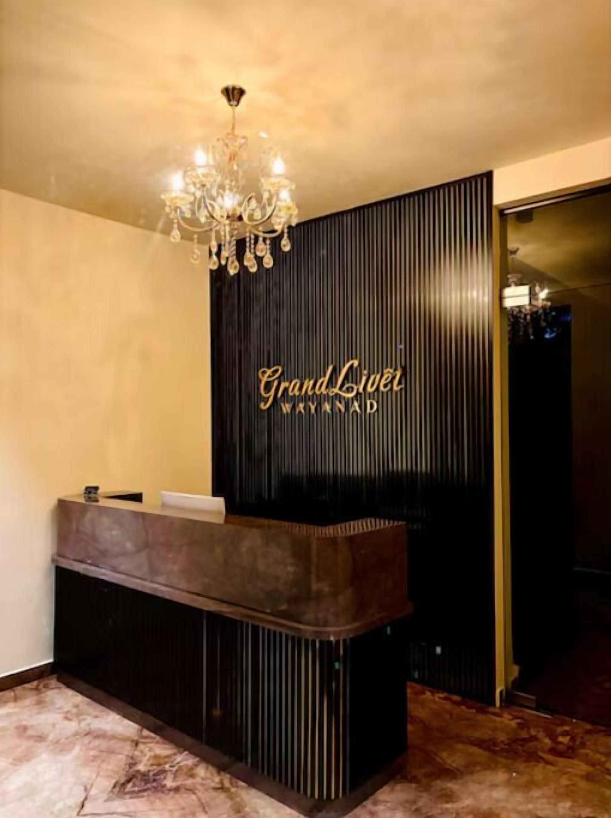 A reception desk with a dark wood finish and a chandelier above.