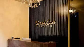A reception desk with a dark wood finish and a chandelier above.