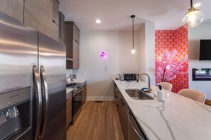 Cocina moderna con electrodomésticos de acero inoxidable, encimera de mármol blanco y un letrero de neón.