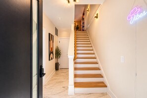 Una escalera con peldaños de madera y un letrero de neón en la pared.