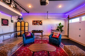 Una habitación con dos sillones azules, una mesa de fútbol de mesa, un dardo y un tapete estampado.