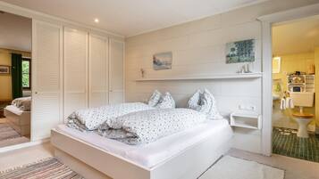 A bedroom with a large bed, a walk-in closet, and a bathroom visible through an open door.
