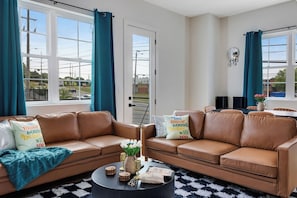 A living room with two brown leather sofas, a coffee table, and a TV. - The Main Stage - Rooftop Hot Tub/Game Room/Groups (Nashville)