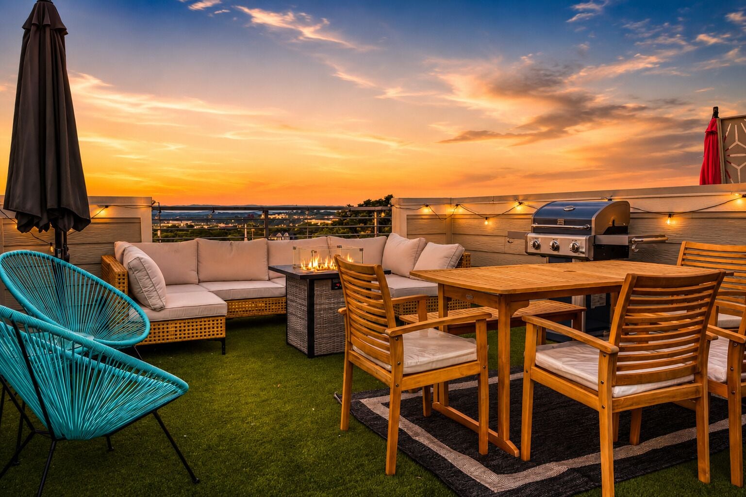 A rooftop patio with a grill, seating area, and a view of the cityscape at sunset.