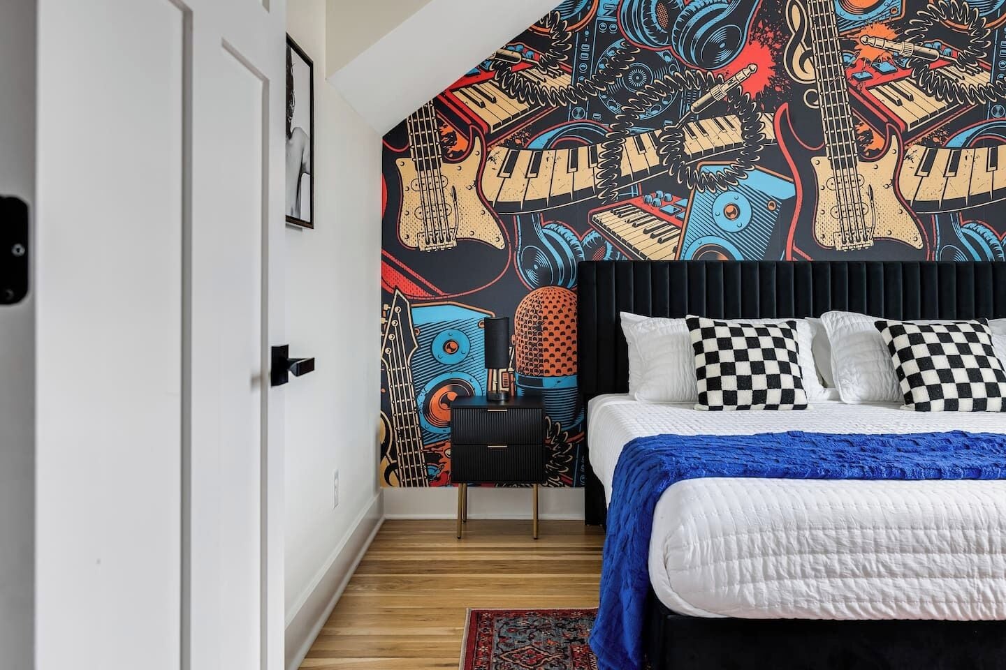 A plush queen bed and bold music-inspired mural create a stylish retreat where comfort meets Nashville character.