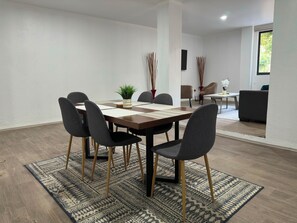 A modern dining area with a wooden table, six chairs, and a patterned rug. - 2-bedroom apartment in vibrant Ciudad de Mexico Roma Norte (Ciudad de México)