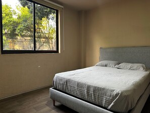 Une chambre à coucher avec un lit, une fenêtre et une vue sur les arbres.