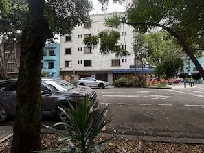 A street view with parked cars, a building with multiple floors, and a tree in the foreground. - 2-bedroom apartment in vibrant Ciudad de Mexico Roma Norte (Ciudad de México)