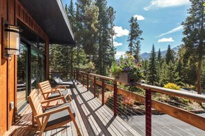 A wooden deck with outdoor seating, a railing, and a view of a forest and mountains. - Private Wooded Breck Retreat - Sauna, Wet Bar & Mtn Views (Breckenridge)