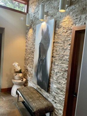 A stone wall with a framed artwork, a bench, and a window. - Private Wooded Breck Retreat - Sauna, Wet Bar & Mtn Views (Breckenridge)