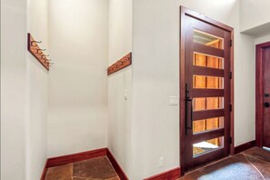 A hallway with a wooden door, a coat rack, and a stone-tiled floor. - Private Wooded Breck Retreat - Sauna, Wet Bar & Mtn Views (Breckenridge)